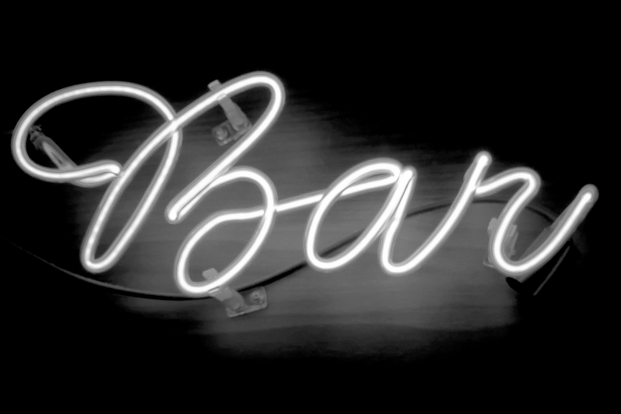 Leuchtendes Neon-Barschild in Schreibschrift vor dunklem Hintergrund