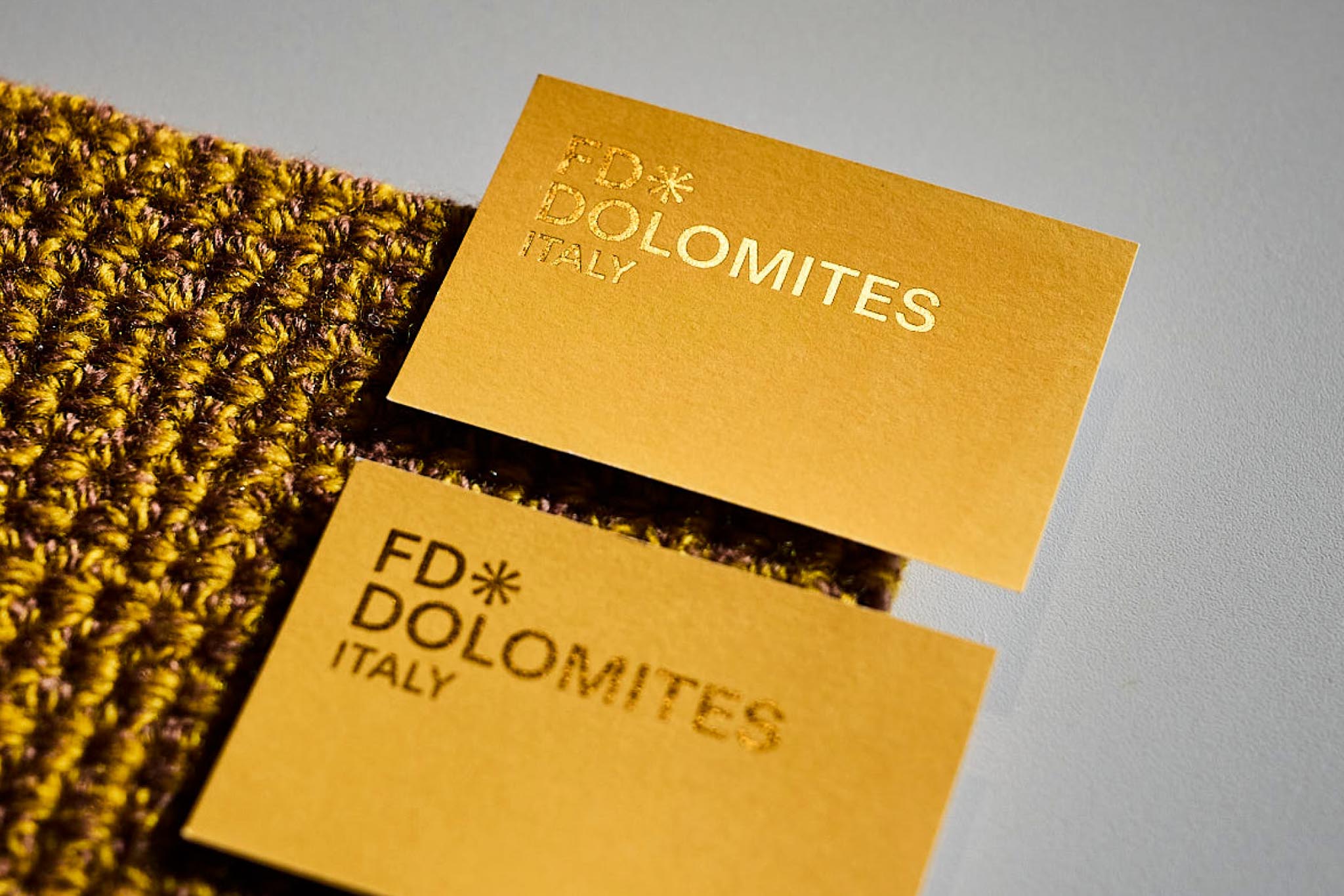 Zwei goldene Visitenkarten, FD Dolomites Italy, auf Textil.