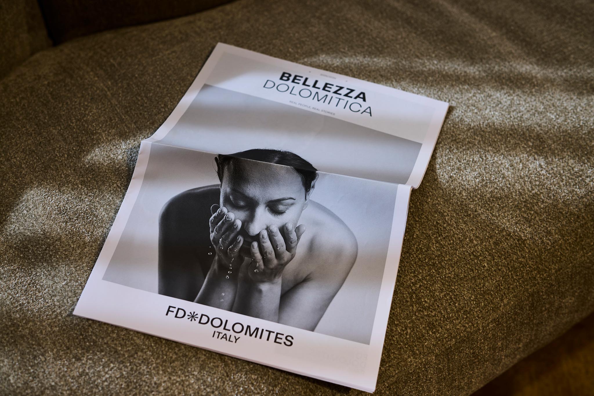 Magazin geöffnet auf Sofa, Frau mit Wasser im Gesicht, Text: FD Dolomites Italy
