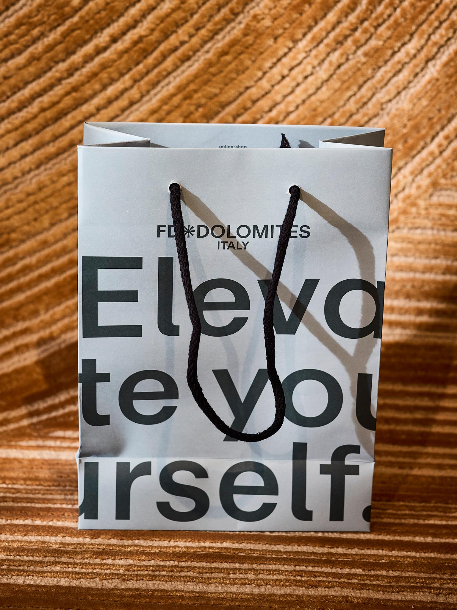 Einkaufstüte mit Aufschrift 'FD Dolomites Italy' auf Teppichboden